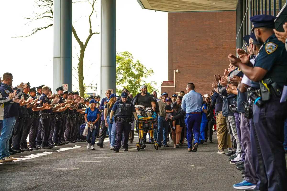 NYPD Det. Corey Fisher was cheered by police officers after he was released from Jamaica Hospital Medical Center days after he was in a “friendly fire” incident.