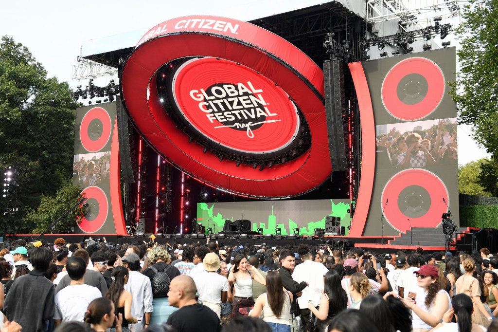 A large stage at the Global Citizen Festival in Central Park with a crowd of people in front of it.