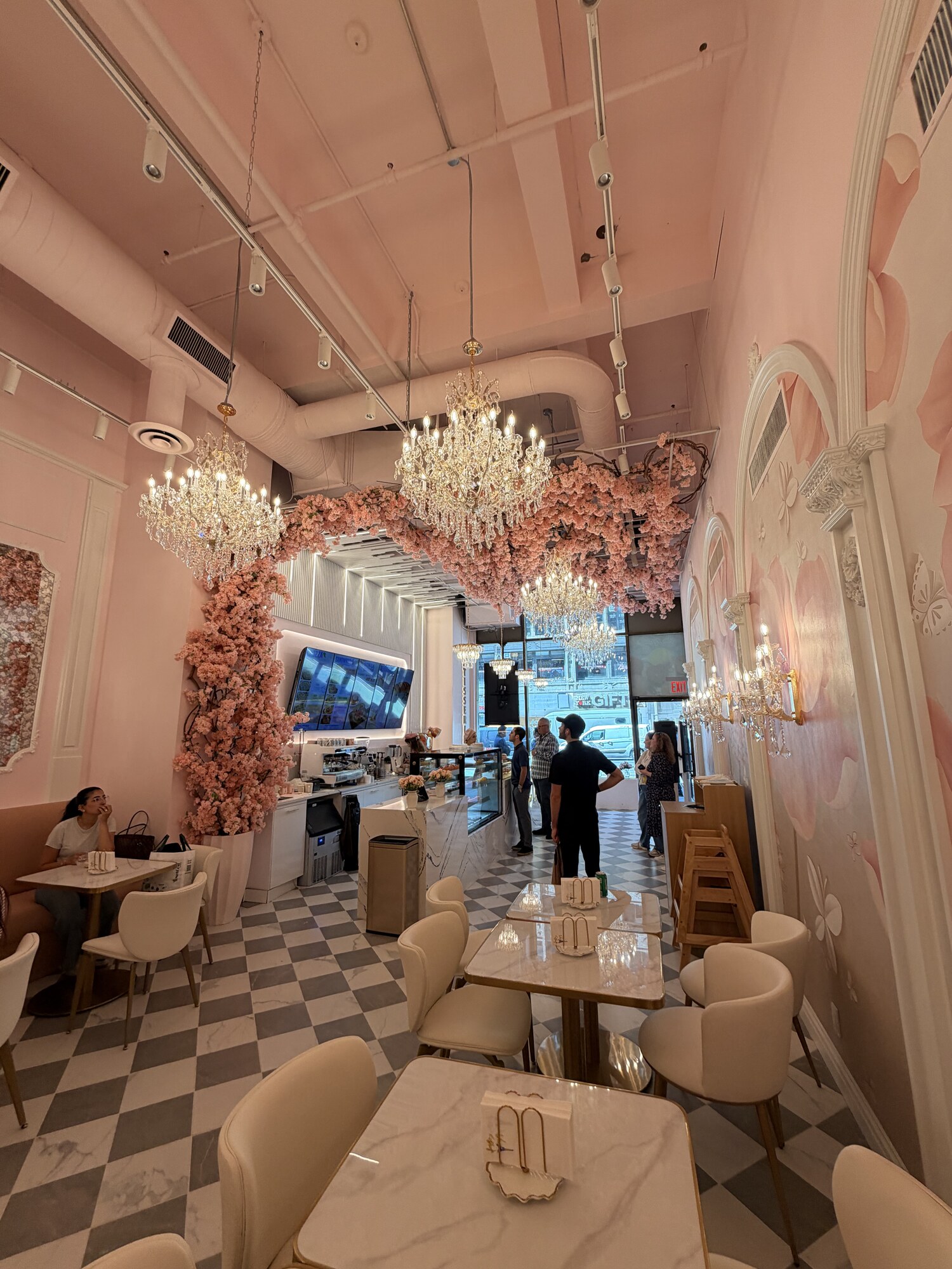 Dining room at Viva La Dough Midtown with pink walls, chandeliers and marble tables