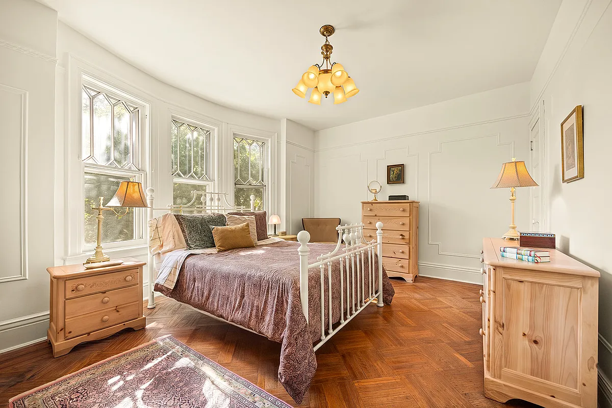 bedroom with wood floor, white walls with wall moldings