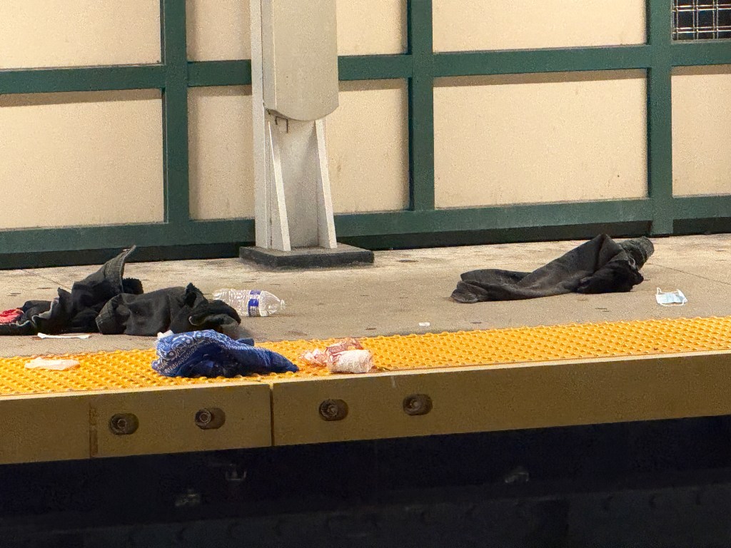 Crime scene with clothing and debris on the platform of the Woodhaven Boulevard subway station.