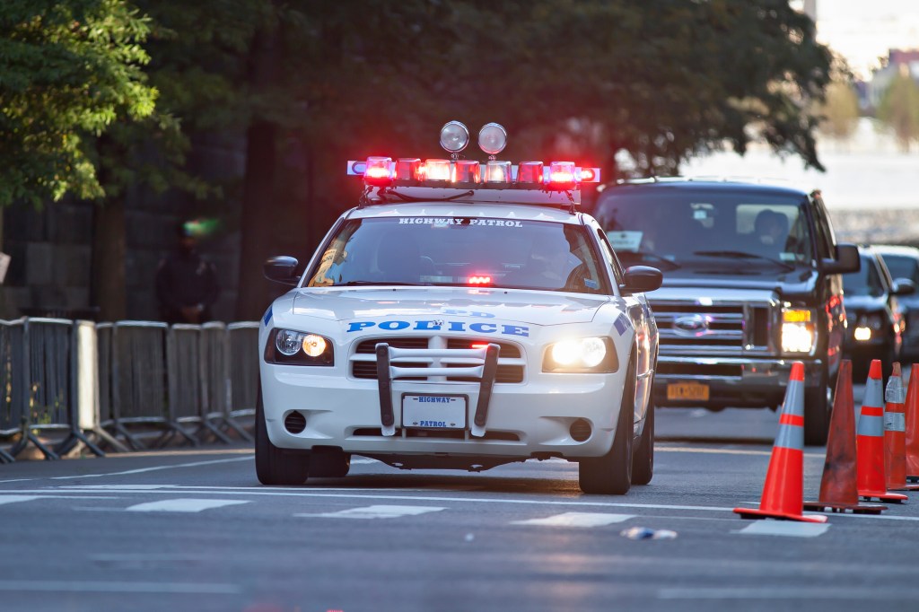 NYPD Highway Patrol car escorting vehicles in New York City.