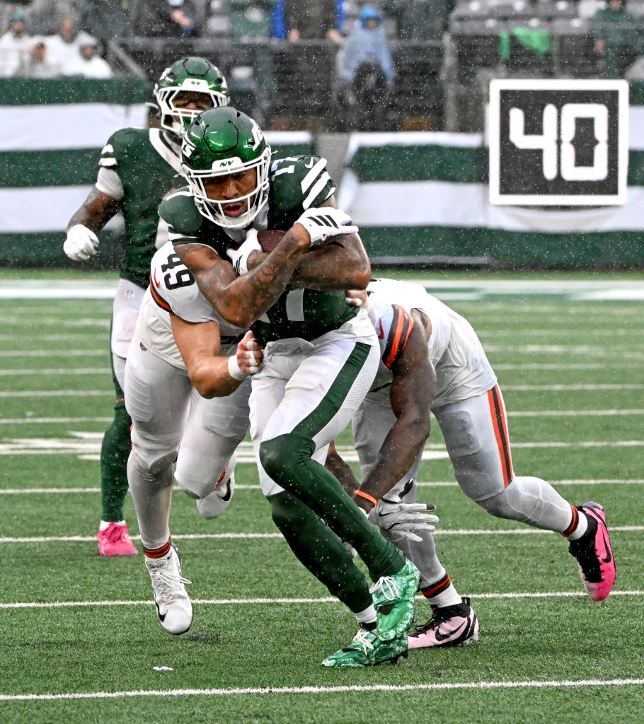 New York Jets wide receiver Tim Patrick runs the ball as he is tackled by Cleveland Browns linebackers Quincy Williams and Carson Schwesinger.