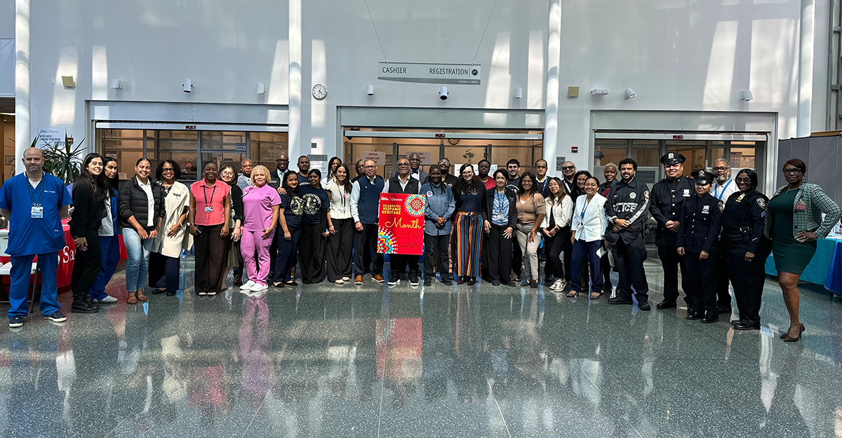 NYC Health + Hospitals/Queens leadership, staff, and community partners—including members of the NYPD—gather in the hospital atrium to celebrate the launch of Hispanic Heritage Month and the Community Health Fair.