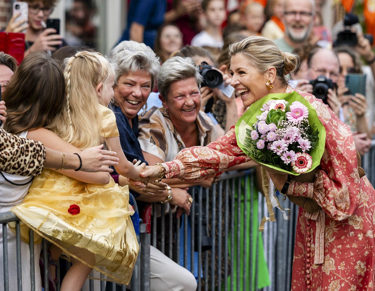With a bouquet tucked into her arm, Máxima greets young well-wishers gathered for her visit to Urk.