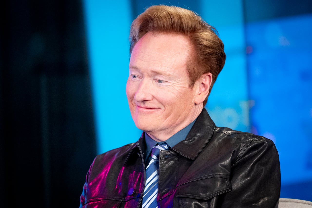 A smiling red-haired man in leather jacket
