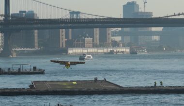The yellow Electra EL2 Ultra Short demonstrator approaching the Downtown Skyport helipad on the East River with the Manhattan Bridge behind