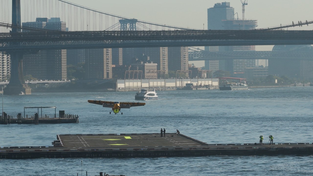 The yellow Electra EL2 Ultra Short demonstrator approaching the Downtown Skyport helipad on the East River with the Manhattan Bridge behind