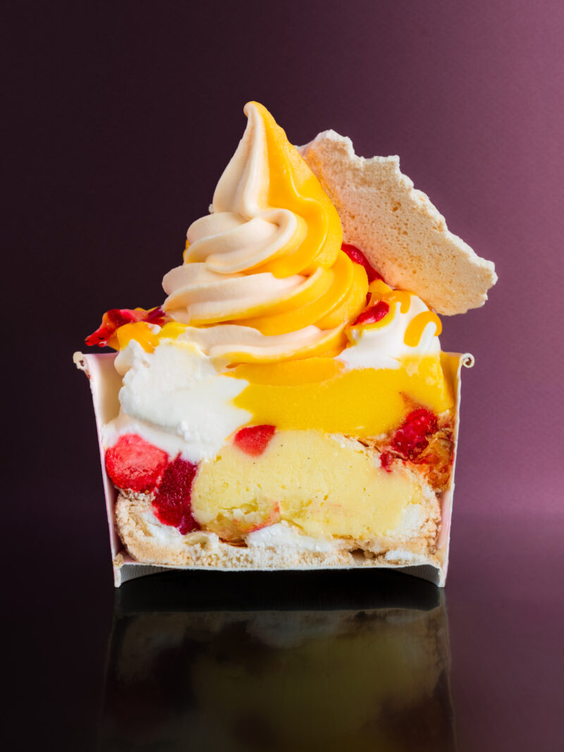 A cross-section of a Softville NYC layered dessert featuring soft-serve ice cream, fruit filling, and meringue.