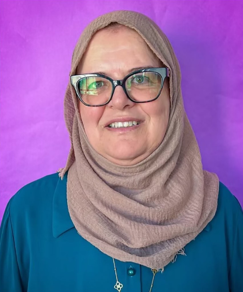 Maysa Jarara wearing a hijab and glasses in front of a purple background.