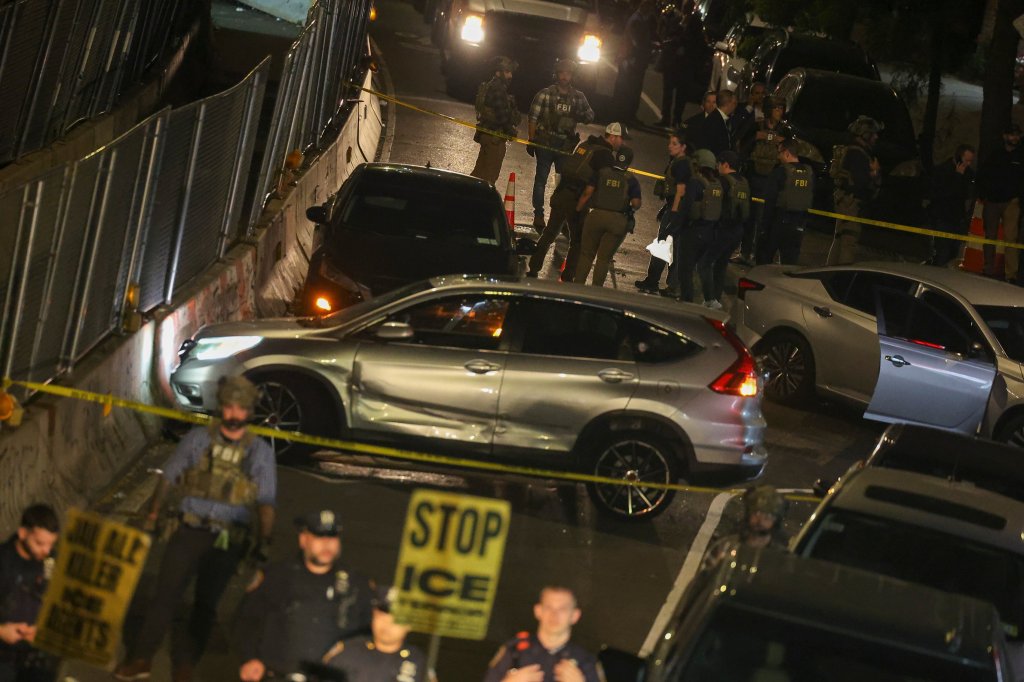 Protesters hold signs reading "Stop ICE" near a crime scene cordoned off with yellow police tape, following a shooting involving an ICE officer.