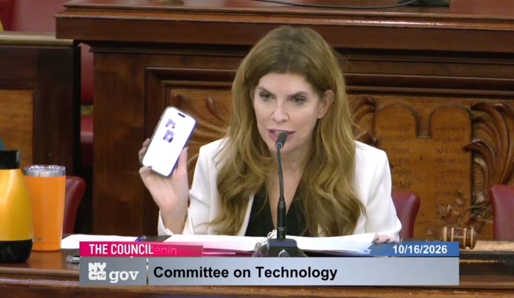 New York Council Speaker Julie Menin holds up a smartphone displaying AI-generated images during a Committee on Technology hearing.