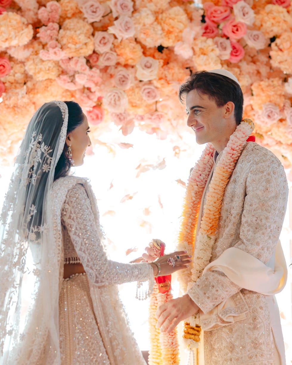 A couple exchanging vows in front of a floral backdrop during a wedding ceremony.