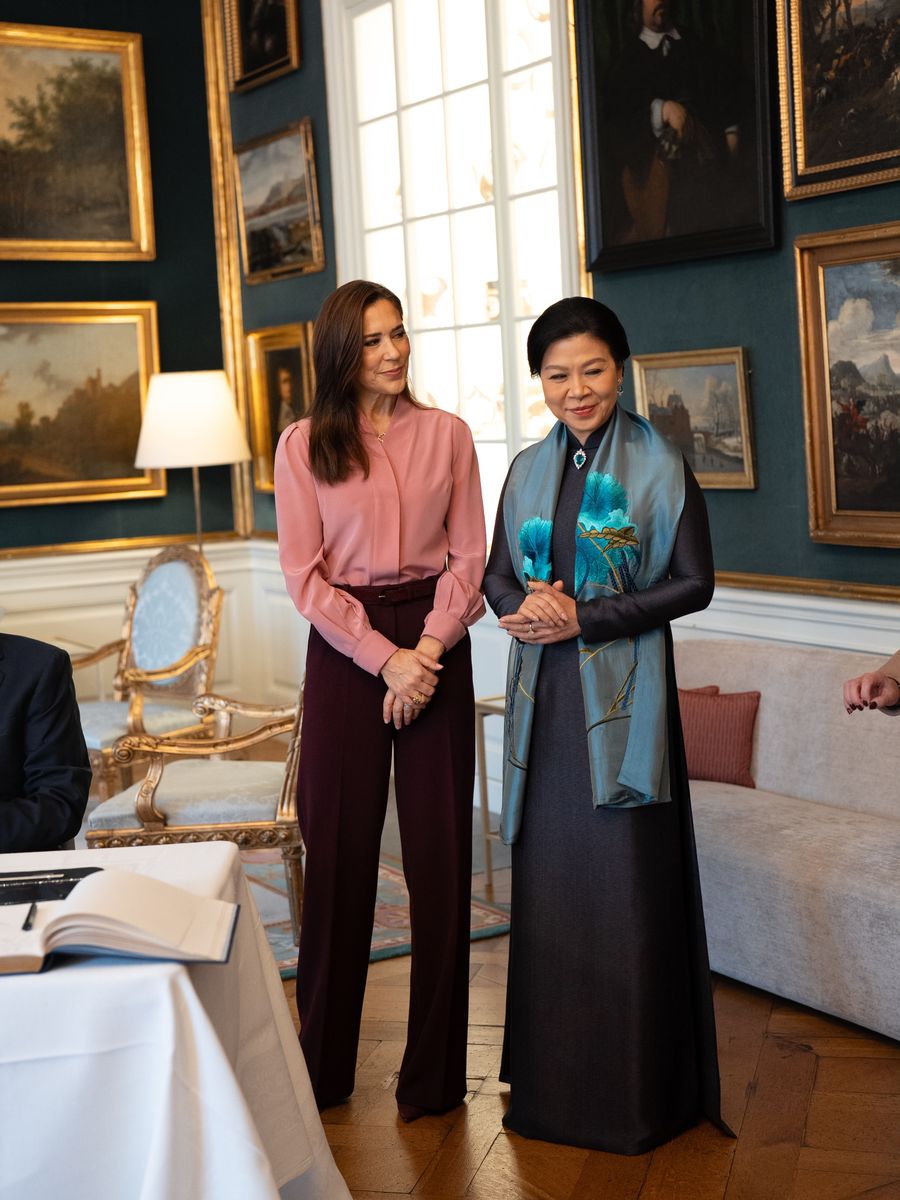 Queen Mary embraced an elegant color combination, pairing a soft pink blouse with burgundy wide-leg trousers for the official farewell at Amalienborg Palace.