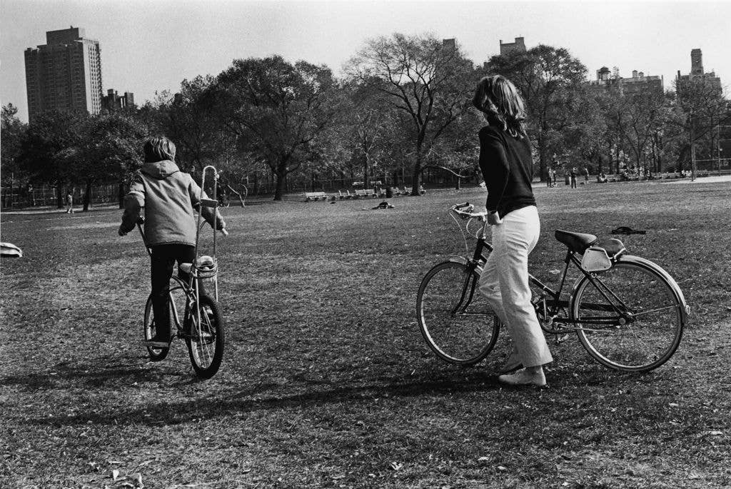 Jacqueline Kennedy Onassis (1929 - 1994), former US first lady and the wife of Greek shipping magnate Aristotle Onassis, and her son, John F. Kennedy Jr., ride bikes through Central Park, New York, New York, November 8, 1970