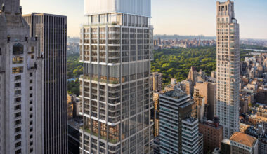 A tall, modern skyscraper with glass windows in an urban setting, surrounded by other high-rise buildings, and a park visible in the background.