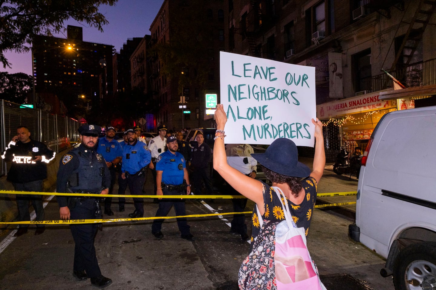 A woman held a sign while confronting police near the scene where a federal immigration agent shot a man in the Marble Hill Thursday night.