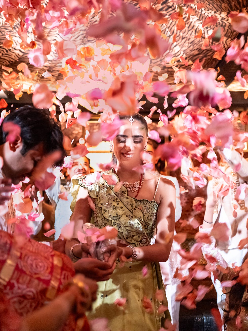 A joyful celebration with a woman in a traditional dress surrounded by a shower of colorful flower petals.