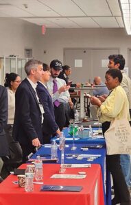 Attendees talking with exhibitors at the tables.