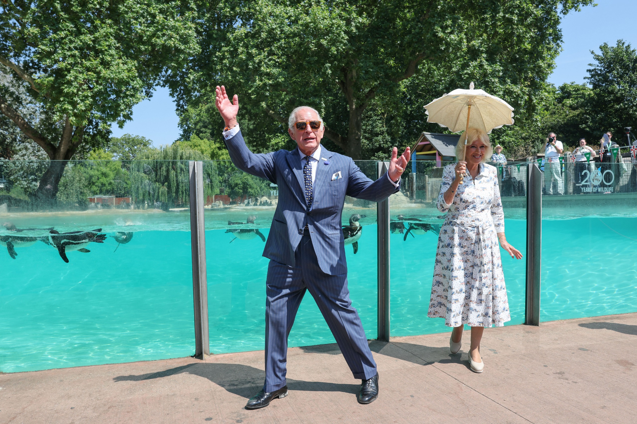 King Charles and Queen Camilla standing in front of the penguin enclosure at the London Zoo