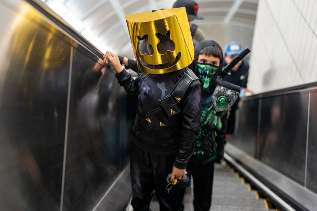 A child rides the escalator dressed as a variant of Marshmello in route to Comic Con at the Jacob K. Javits Convention Center on Friday, Oct. 9, 2026, in New York. (AP Photo/David 'Dee' Delgado)