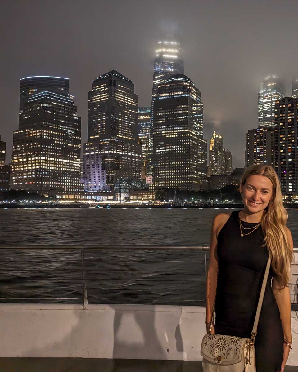Bailey poses for a photo at night on a dinner cruise in New York City on the front deck with the city in the background