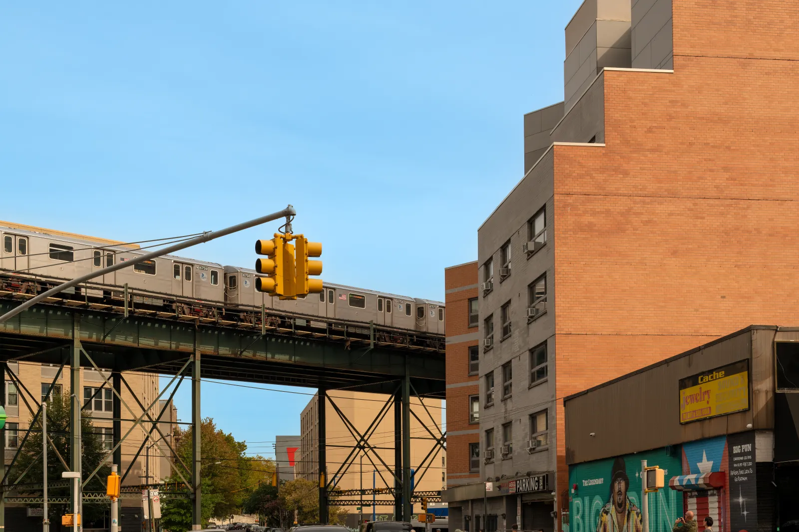 New York, NY, United States - September 30, 2025: The urban environment of The Bronx displays a mix of transportation infrastructure and vibrant street murals on local storefronts.