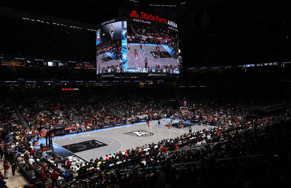 Wide-angle shot of a basketball game between the Las Vegas Aces and Atlanta Dream at State Farm Arena, showing players on the court and a large scoreboard overhead.