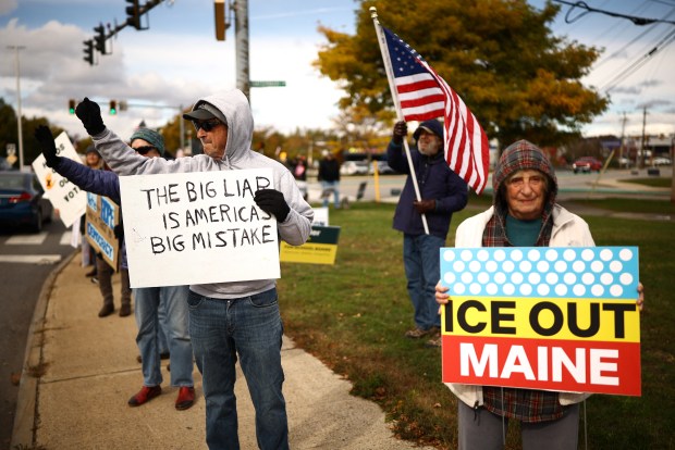 People hold signs during a "No Kings: Vote Early" demonstration in Portland, Maine on Oct. 17, 2026. (Photo by CHARLY TRIBALLEAU / AFP via Getty Images)