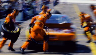 A blurry image of an auto racing pit crew servicing a race car mid-race.