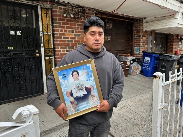 William Lojano, son of Mesias Lojano, who was fatally stabbed on a Woodhaven Blvd. J train, is pictured holding a photo of his father outside his home on 97th St. in Corona, Queens, on Thursday, Oct. 1, 2026. (Kerry Burke / New York Daily News)