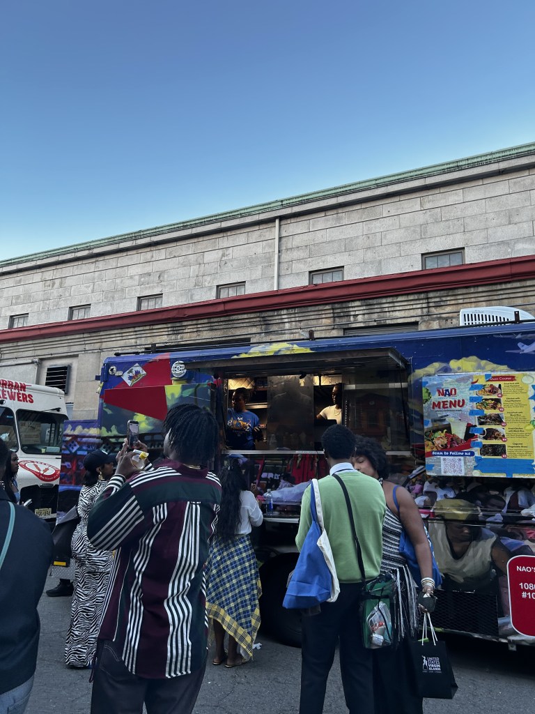 Attendees gather at Nao’s Caribbean Flavors, a Haitian food truck serving traditional Haitian cuisine, during CultureCon 2026 at the Brooklyn Navy Yard. Photo by Catherine Roth / The Haitian Times
