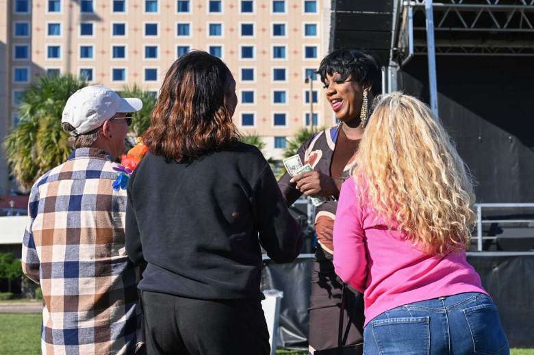 spectators hand a drag queen tips during a show held outside