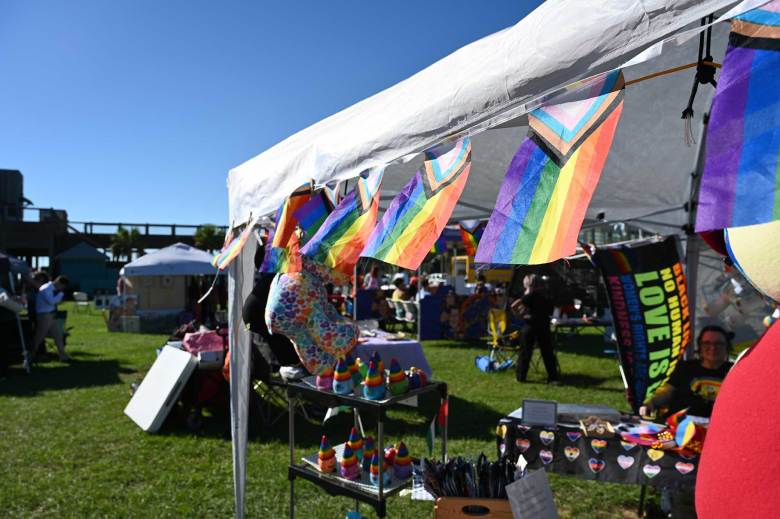 pride flags wave in the wind on a vendor’s tent