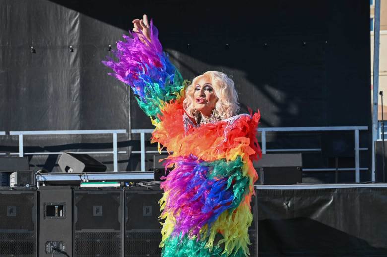 A drag queen wears a rainbow feathered jacket as she performs at a drag show