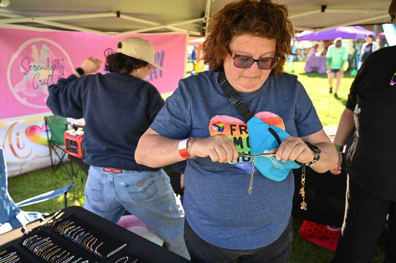 someone wearing a pride shirt that says ‘Free Mom Hugs’ makes jewelry