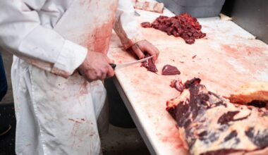 A butcher cutting beef on a white table.
