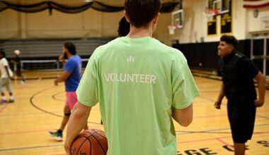 Volunteer works with students on a basketball court for YMCA programming.