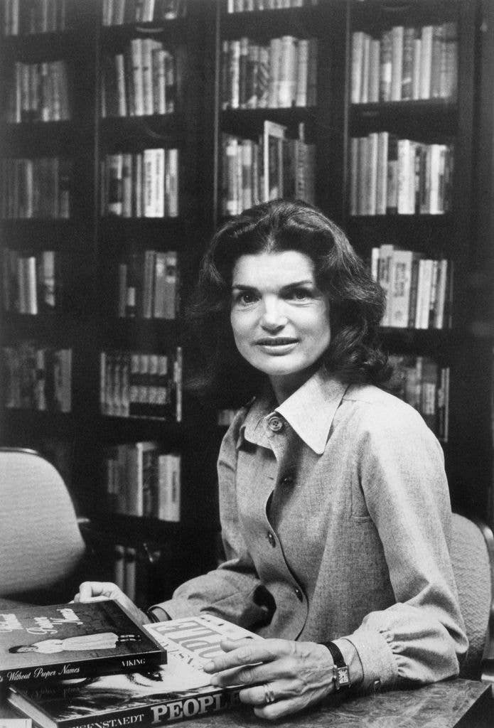 For the first time since she earned $56.75 per week in 1952, as a camera girl for the old Washington Times Herald, Jacqueline Kennedy Onassis, 46, has a job here. She is shown as a Consulting Editor for the Viking Press, Inc. book publisher. On her first day in the office, September 22nd, Thomas H. Guinzburg, President of Viking, introduced her to the staff and arranged for her to be photographed in a book lined conference room. Commenting on Jackie joining the Viking staff, Guinzburg observed, "one is not unmindful of the range of contacts the lady has."