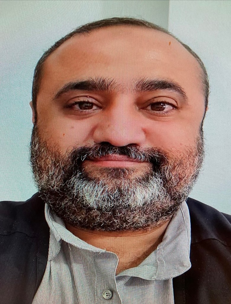 Headshot of Saleem Alzaq with a short beard and mustache, wearing a collared shirt and jacket.