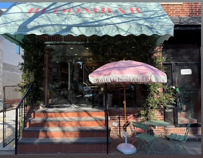 The green and pink awning and storefront of a BloomBar Café et Fleurs location in Brooklyn