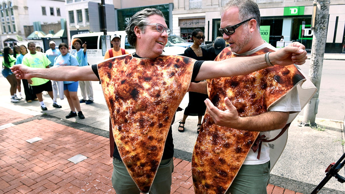 NEW HAVEN, CT - AUGUST 5: Louis Mangini, left, constituent services manager for U.S. Rep. Rosa DeLauro, gets assistance securing a pizza costume from Colin Caplan, Founder of Taste of New Haven, before a press conference on the New Haven Green on Aug. 5, 2026 announcing a new Guinness World Record attempt for the largest pizza costume party. (Arnold Gold/Connecticut Post via Getty Images)