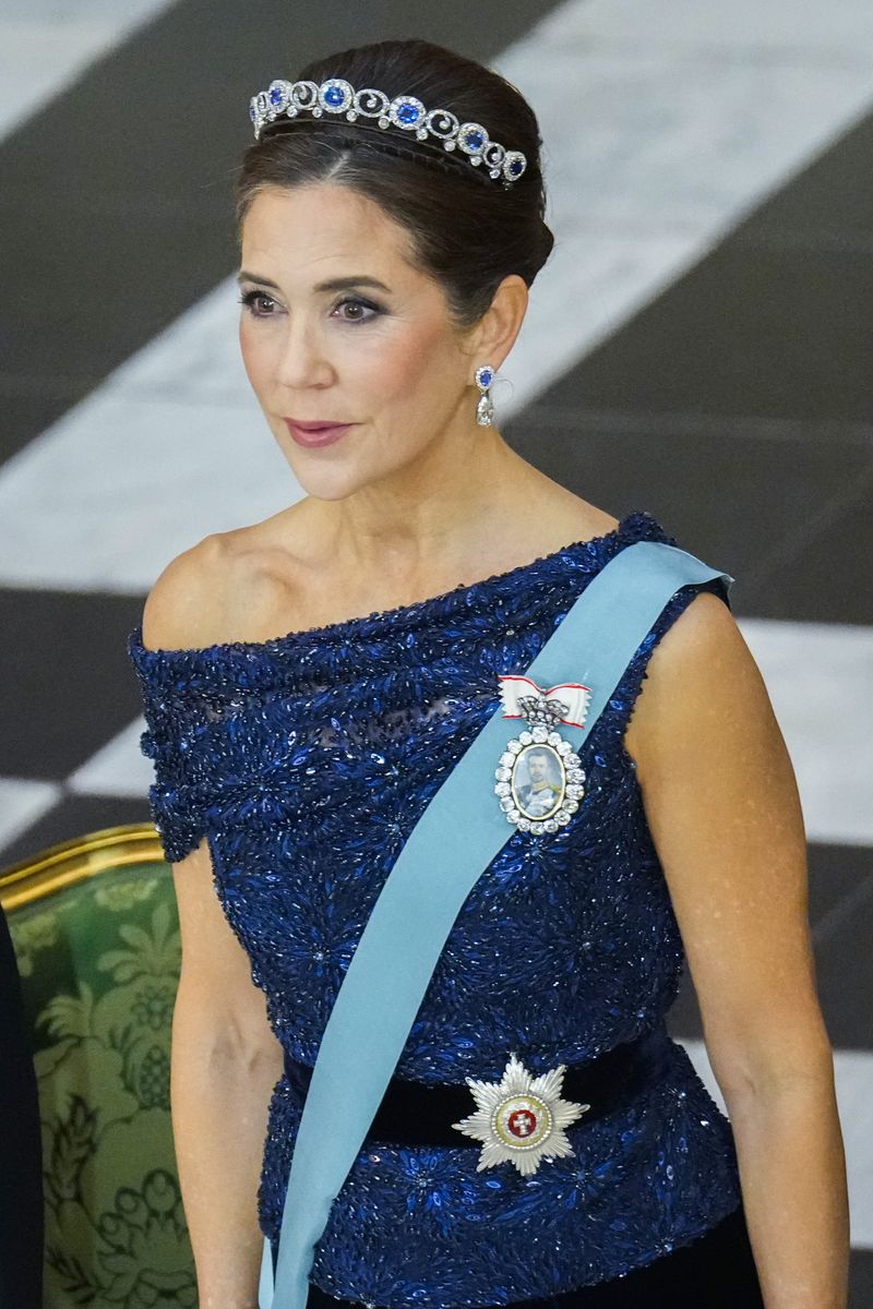 Queen Mary completed her glamorous state banquet ensemble with an elegant updo, royal decorations and dazzling jewelry.
