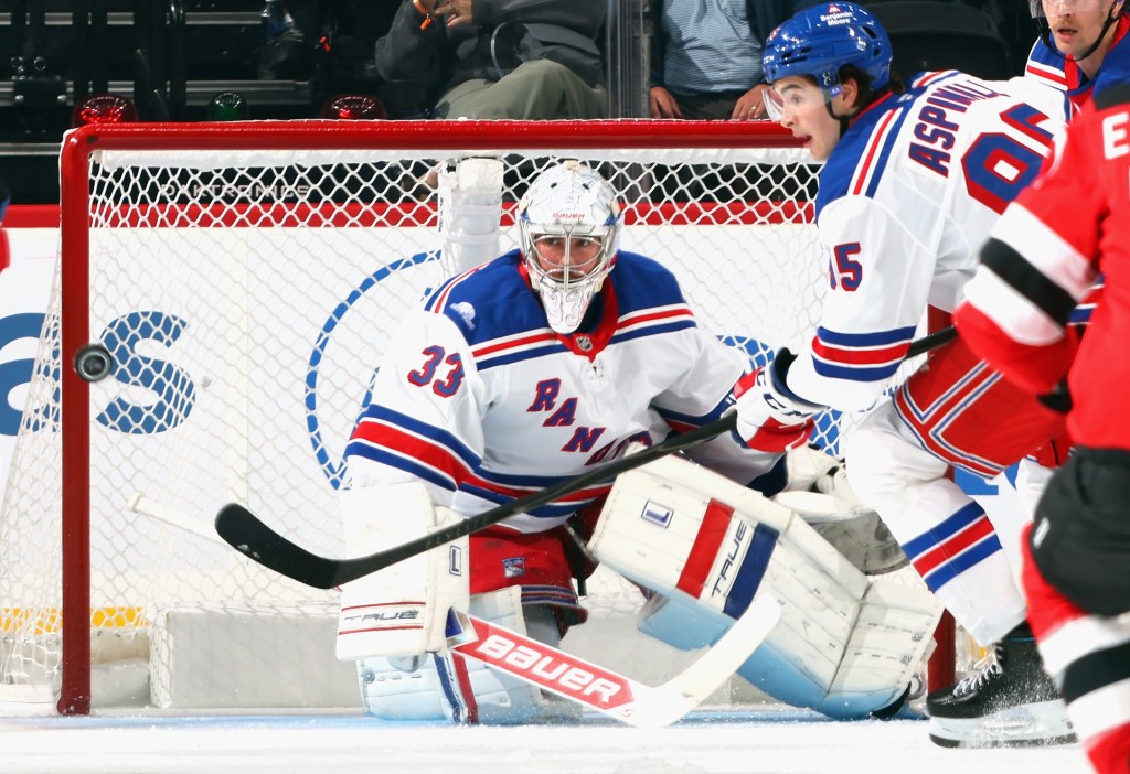 New York Rangers goaltender Dylan Garand (#33) makes a save against the New Jersey Devils as the puck bounces off the net.