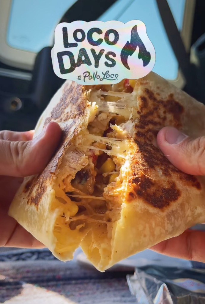 A grilled El Pollo Loco burrito being pulled apart, revealing melted cheese and filling.
