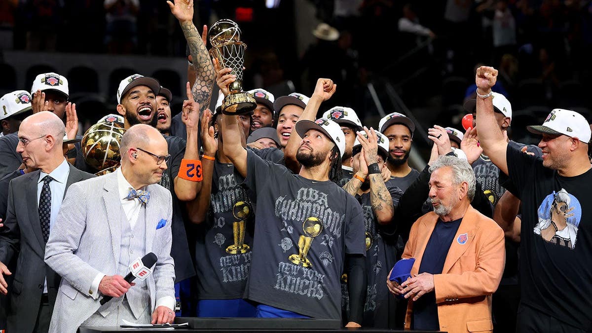 Jalen Brunson lifts the Bill Russell NBA Finals Most Valuable Player Award trophy.