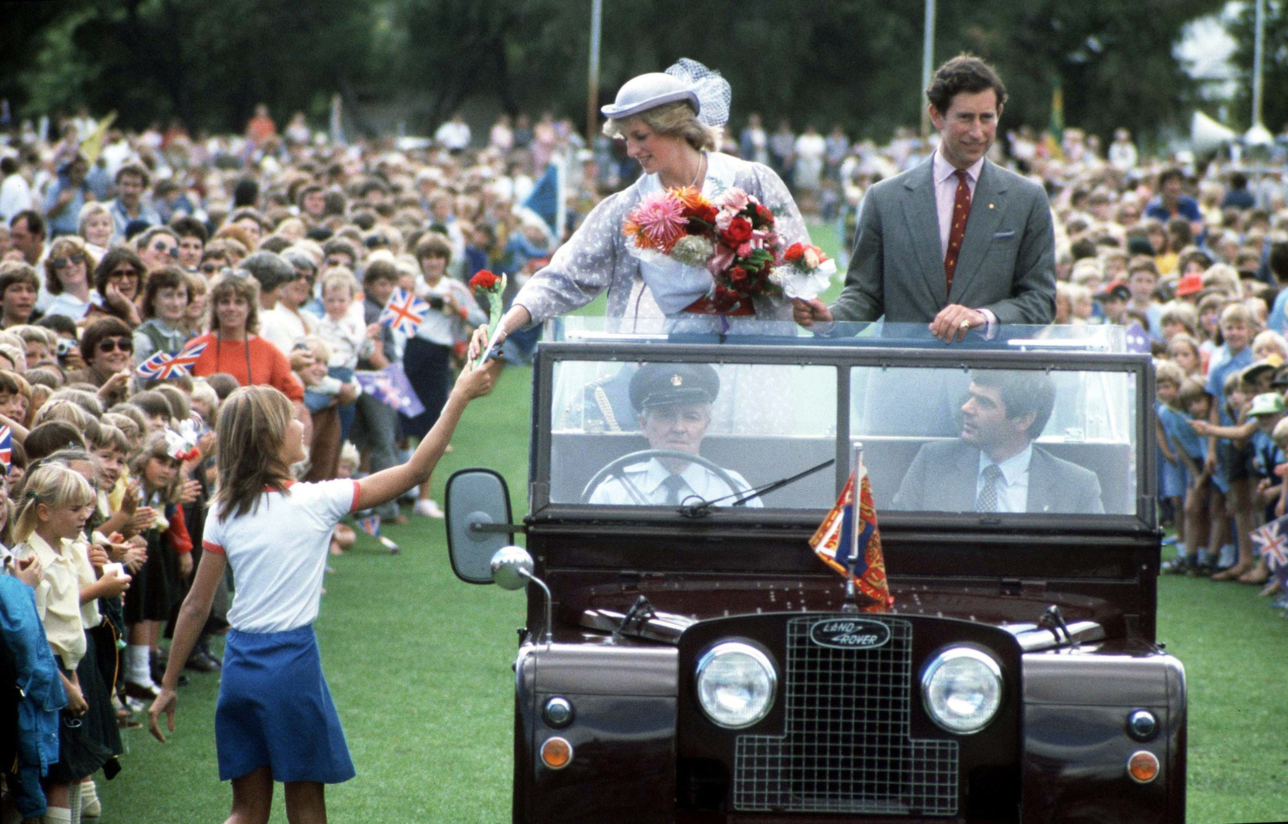 Princess DIana and Prince charles riding in an open top car greeting fans