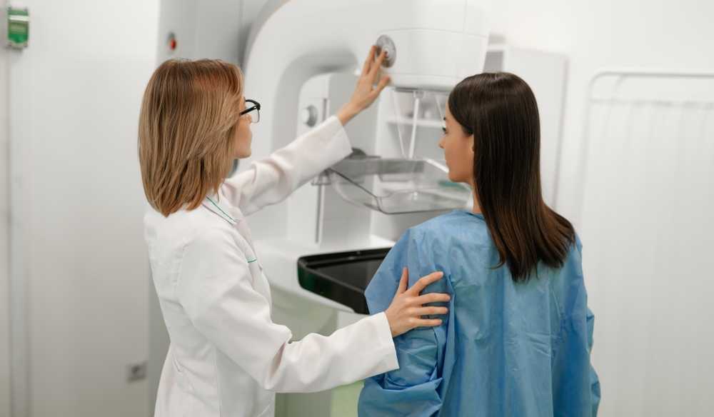 woman with doctor undergoes mammogram to check for breast cancer
