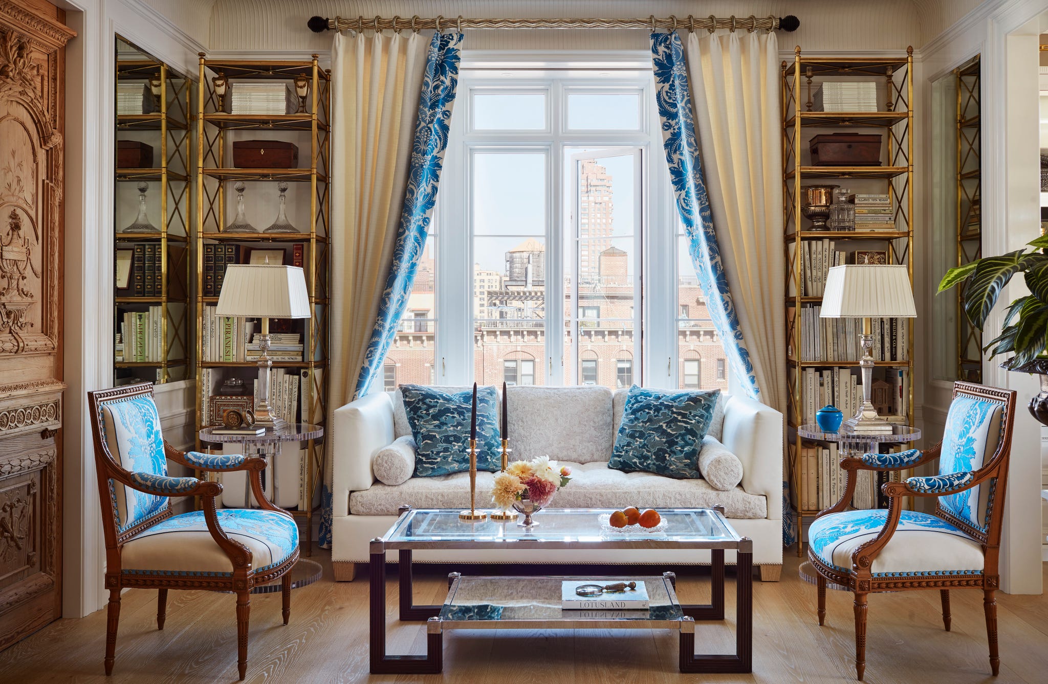 Marshall Watson New York Apartment Living Area living are with couch in front of window and two chairs, two bookshelves, and a coffee table