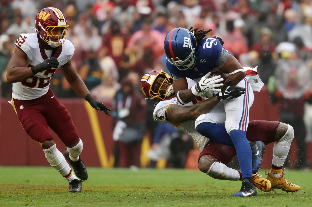 Giants' Najee Harris (23) is tackled by Washington Commanders' Frankie Luvu (4) during the second quarter of an NFL football game at Northwest Stadium in Landover, Md., Sunday, Oct. 11, 2026.